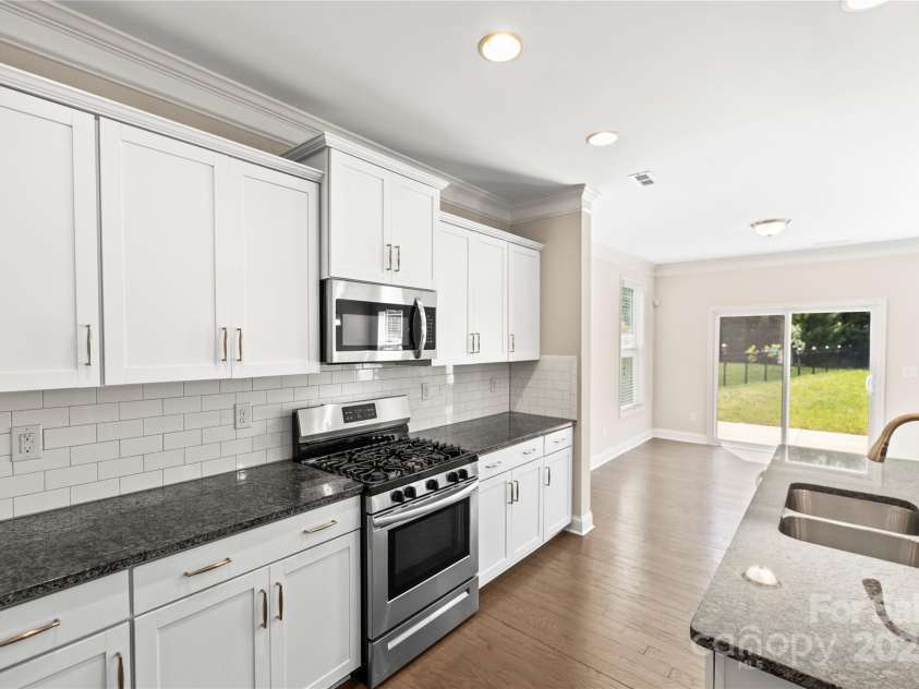 3023 Spinner Court, Denver, NC 28037.  MLS# CAR4142435, YatesRealty ID 6943. The kitchen features white, crisp cabinets and granite countertops, seamlessly connecting to the family room, creating a stylish and functional space for cooking and gathering with loved ones.
