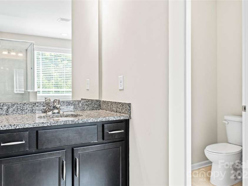 3023 Spinner Court, Denver, NC 28037.  MLS# CAR4142435, YatesRealty ID 6943. The primary bathroom features dual vanity sinks with sleek granite countertops, offering both style and functionality for daily routines.