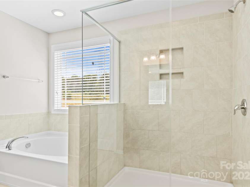 3023 Spinner Court, Denver, NC 28037.  MLS# CAR4142435, YatesRealty ID 6943. The primary bathroom has a modern frameless glass shower and a freestanding tub for soaking, adding a touch of luxury to the space.
