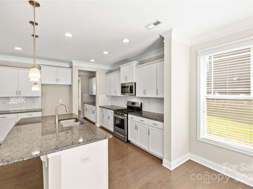 3023 Spinner Court, Denver, NC 28037.  MLS# CAR4142435, YatesRealty ID 6943. The roomy kitchen boasts an abundance of countertop space and cabinets, providing ample room for meal preparation and storage. Light spills in through the windows, accentuating the gleaming surfaces and creating an inviting