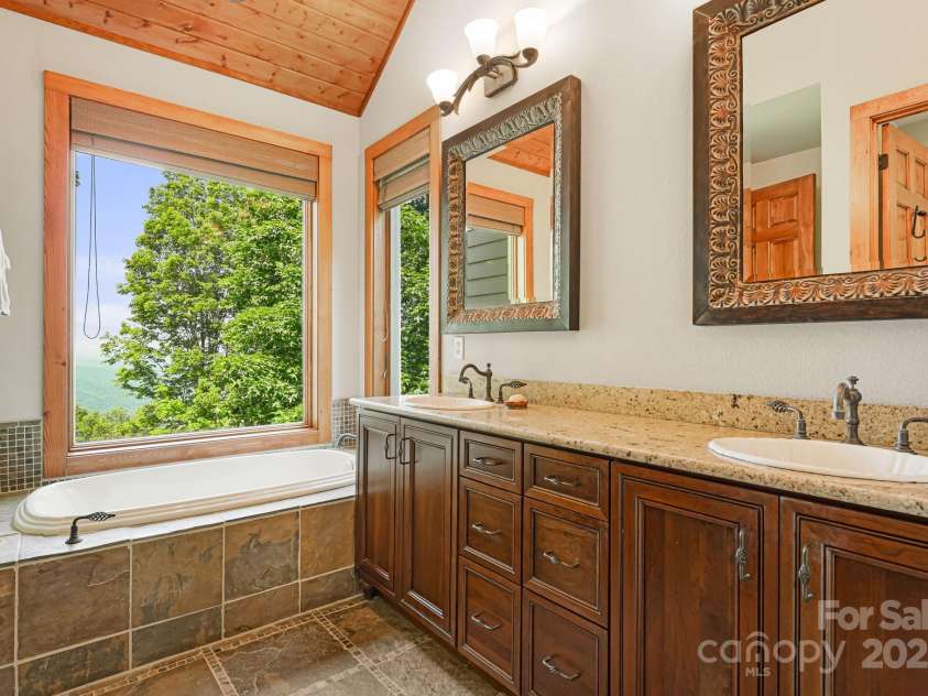 197 Cherry Knob Drive, Mars Hill, NC 28754.  MLS# CAR4271284, YatesRealty ID 7144. Relax in the deep soaking tub set beneath expansive windows offering breathtaking mountain views—paired with custom cabinetry and dual vanities for a luxurious spa-like experience.
