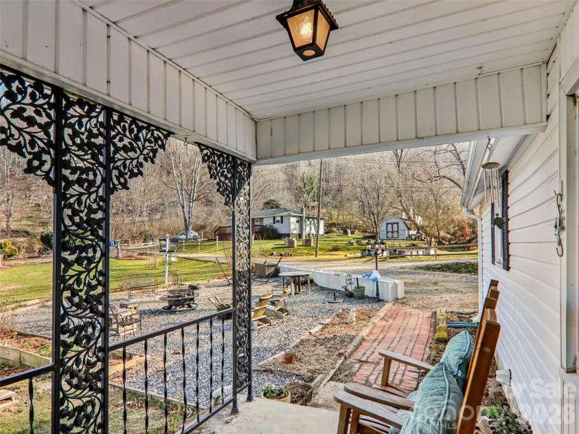 7 Landon Mountain Lane, Weaverville, NC 28787.  MLS# CAR4334252, YatesRealty ID 7316. Covered front porch with decorative ironwork, offering a comfortable spot to relax while overlooking the front yard, gravel patio, and outdoor gathering area.
