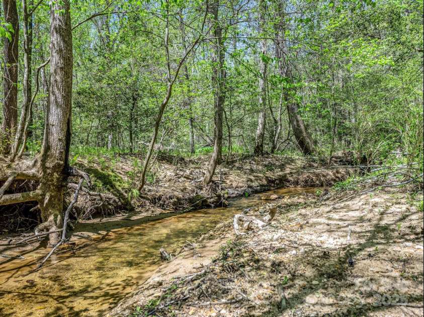241 Pinefield Drive, Tryon, NC 28782.  MLS# CAR4250675, YatesRealty ID 7781. Creek winds through the property with many spots to wade into the water