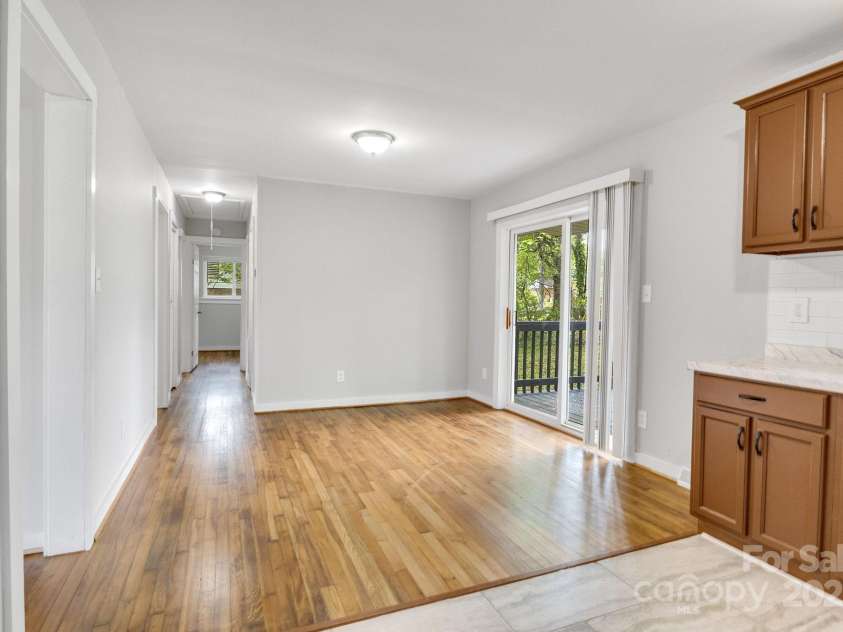 801 Bilmark Avenue, Charlotte, NC 28213.  MLS# CAR4247710, YatesRealty ID 8010. Partial shot of kitchen; primary focus is on dining area, which would be in the center of the photo under the light. Hallway on left leads to and connects the bedrooms. Glass door on right exits to backyard.