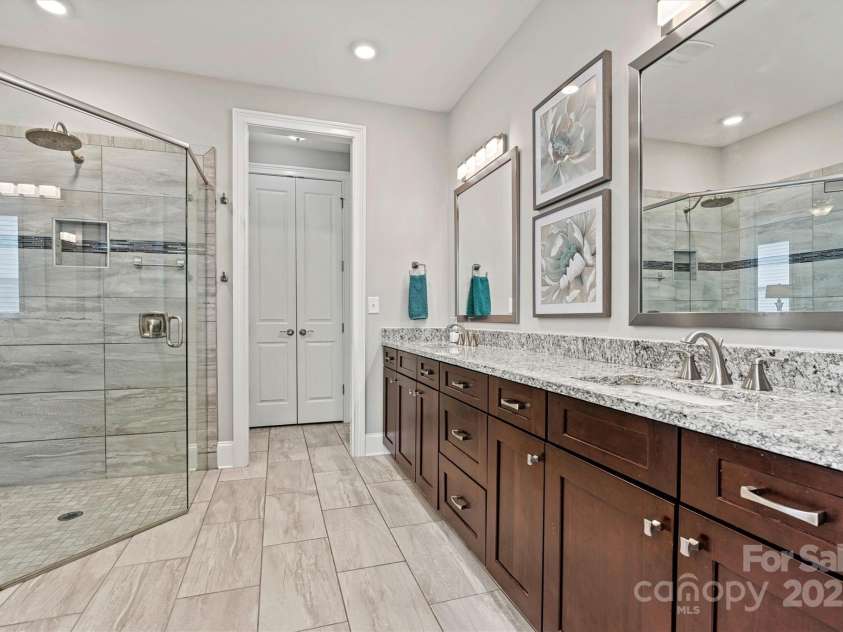 7549 Short Putt Court, Charlotte, NC 28215.  MLS# CAR4248938, YatesRealty ID 8028. The ensuite features dual vanities, a dreamy oversized zero-entry shower, makeup vanity, framed mirrors, and a spacious walk-in closet.