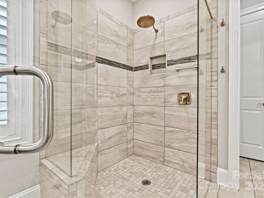 7549 Short Putt Court, Charlotte, NC 28215.  MLS# CAR4248938, YatesRealty ID 8028. The frameless, fully tiled shower with a striking listello accent band and zero-entry design offers a sleek, spa-like experience every day.