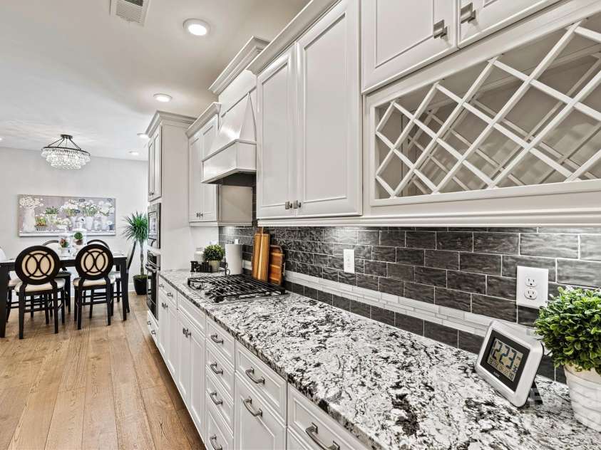 7549 Short Putt Court, Charlotte, NC 28215.  MLS# CAR4248938, YatesRealty ID 8028. The upgraded beveled tile backsplash reflects the light, paired perfectly with gorgeous Level 4 Granite counters, custom wine rack and wide plank wood floors that tie it all together in style.