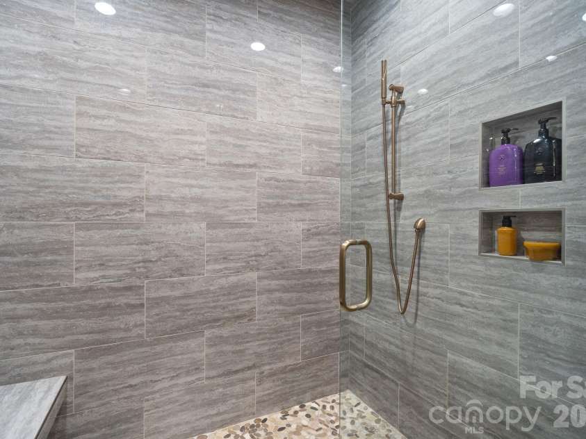 19329 Watermark Drive, Cornelius, NC 28031.  MLS# CAR4406294, YatesRealty ID 8051. Zero entry shower features river rock floor, bench, and multiple shower heads.