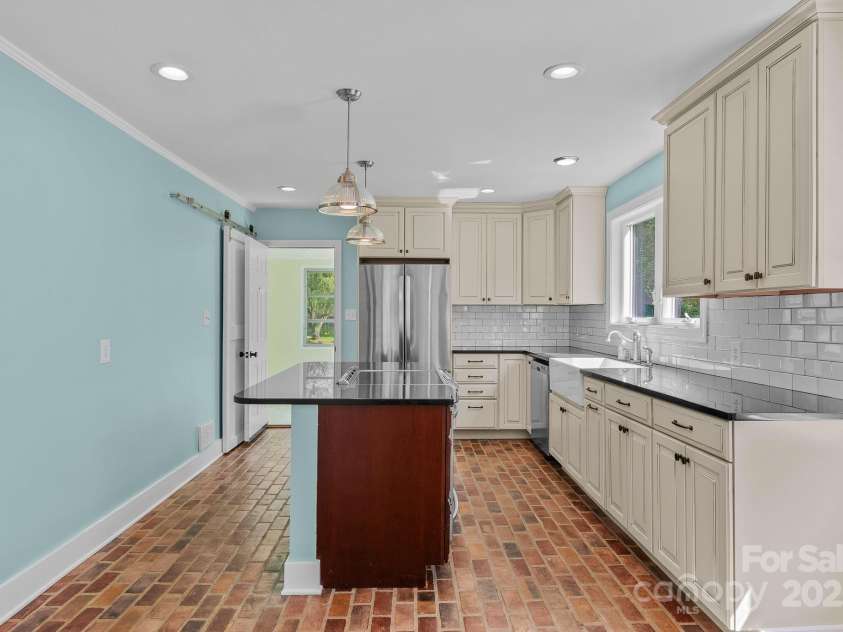 318 Stoney Mountain Road, Hendersonville, NC 28791.  MLS# CAR4235178, YatesRealty ID 8150. At the back left of the kitchen behind the sliding barn door is the laundry area designed for a stackable W/D set.