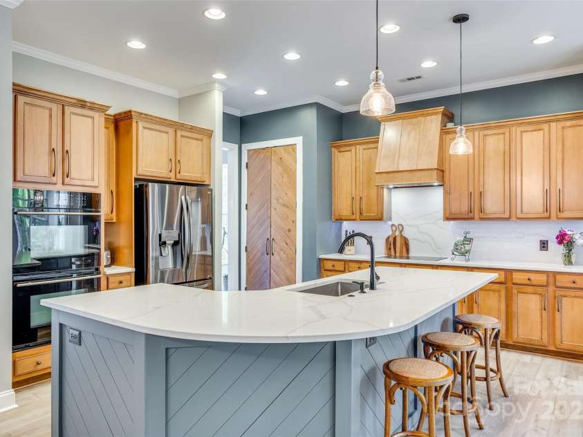 349 Miners Cove Way, Fort Mill, SC 29708.  MLS# CAR4248883, YatesRealty ID 8213. The heart of this home showcases a breathtaking kitchen renovation where masterful design meets functional luxury. Anchoring this culinary showpiece is a stunning oversized island that serves as both a stylish focal poi