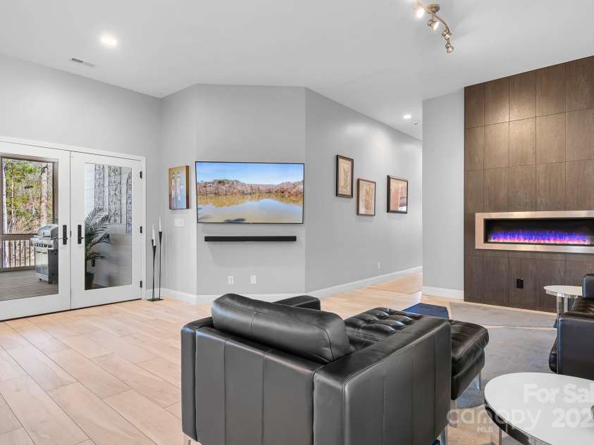 940 Hawk Ridge Drive, Mill Spring, NC 28756.  MLS# CAR4227450, YatesRealty ID 8244. Modern style family room with custom ethanol fireplace and surround. French doors lead to covered and screened in deck space.