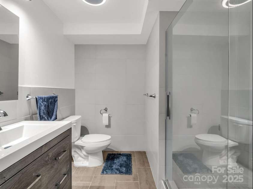 2115 Stoney View Court, Hendersonville, NC 28792.  MLS# CAR4310001, YatesRealty ID 839. Contemporary lower-level bathroom featuring sleek tile finishes, a frameless glass shower, and a modern vanity with clean, minimalist design