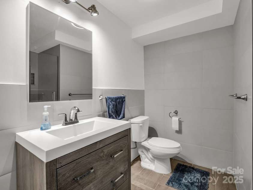 2115 Stoney View Court, Hendersonville, NC 28792.  MLS# CAR4310001, YatesRealty ID 839. Contemporary lower-level bathroom featuring sleek tile finishes, a frameless glass shower, and a modern vanity with clean, minimalist design