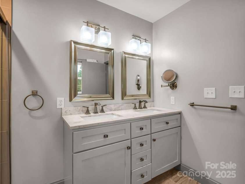 2115 Stoney View Court, Hendersonville, NC 28792.  MLS# CAR4310001, YatesRealty ID 839. Stunning primary bath with a spacious glass-enclosed shower, double vanity with marble countertops, and elegant gold-accented fixtures for a timeless, upscale feel