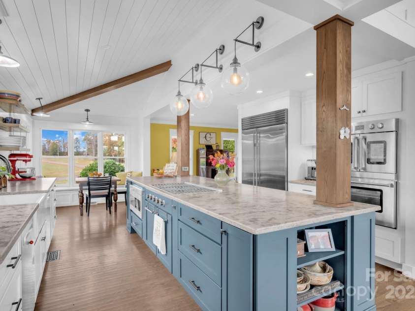1260 Beaver Island Trail Road, Walnut Cove, NC 27052.  MLS# CAR4325171, YatesRealty ID 843. 4-chair breakfast island w/ wood columns and display shelves, pantry cabinet w/ pull-out drawers, under cabinet lighting, and cathedral and vaulted shiplap ceilings w/ suspended beams