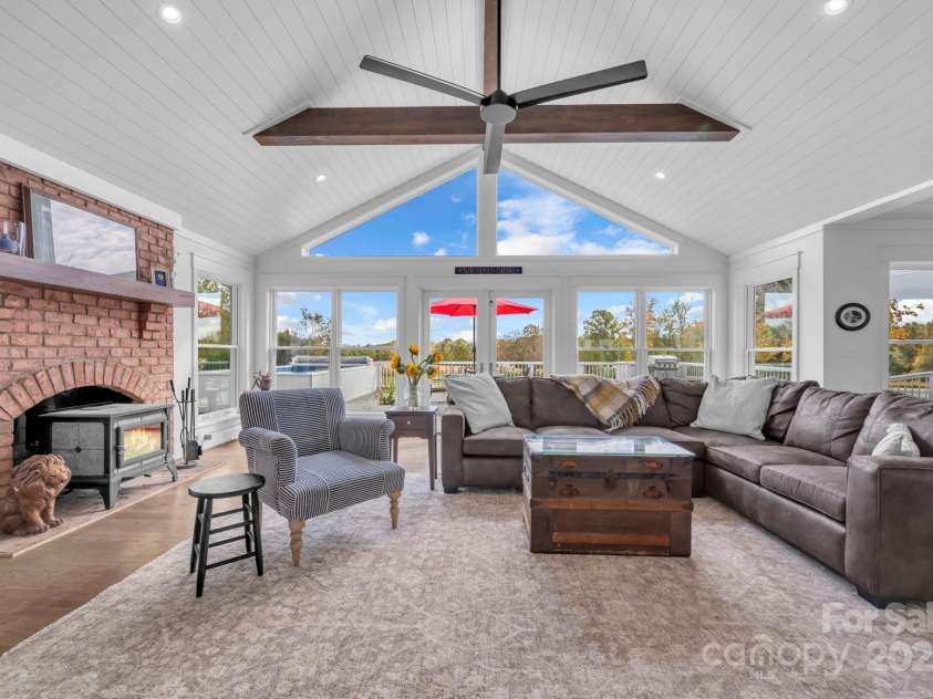 1260 Beaver Island Trail Road, Walnut Cove, NC 27052.  MLS# CAR4325171, YatesRealty ID 843. Great room w/ cathedral ceilings & exposed wooden beams, brick fireplace w/ Hearthstone wood burning cast iron stove, shiplap ceiling, and large gable window for natural light
