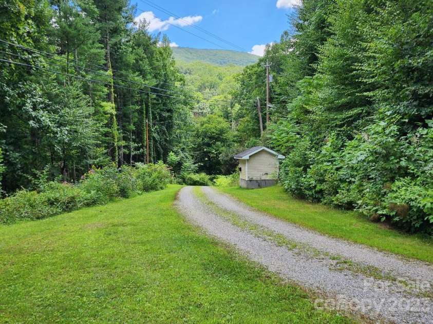160 Snake Den Drive, Burnsville, NC 28714.  MLS# CAR4062924, YatesRealty ID 843. Looking east along driveway with well/pump house for trailer park in distance