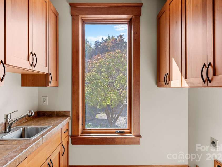 150 Cherry Hill, Mill Spring, NC 28756.  MLS# CAR4201746, YatesRealty ID 8524. Laundry room with sink and storage on main level just inside the door to the garage.  