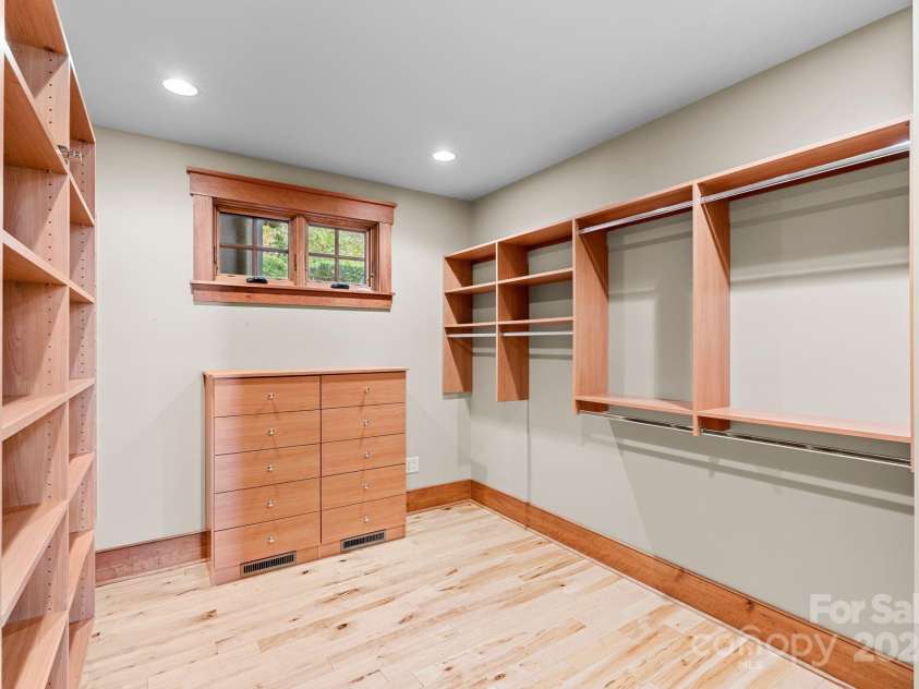 150 Cherry Hill, Mill Spring, NC 28756.  MLS# CAR4201746, YatesRealty ID 8524. One of two massive walk-in-closets in the primary suite. Both have extensive custom built-in storage cabinets and shelving.