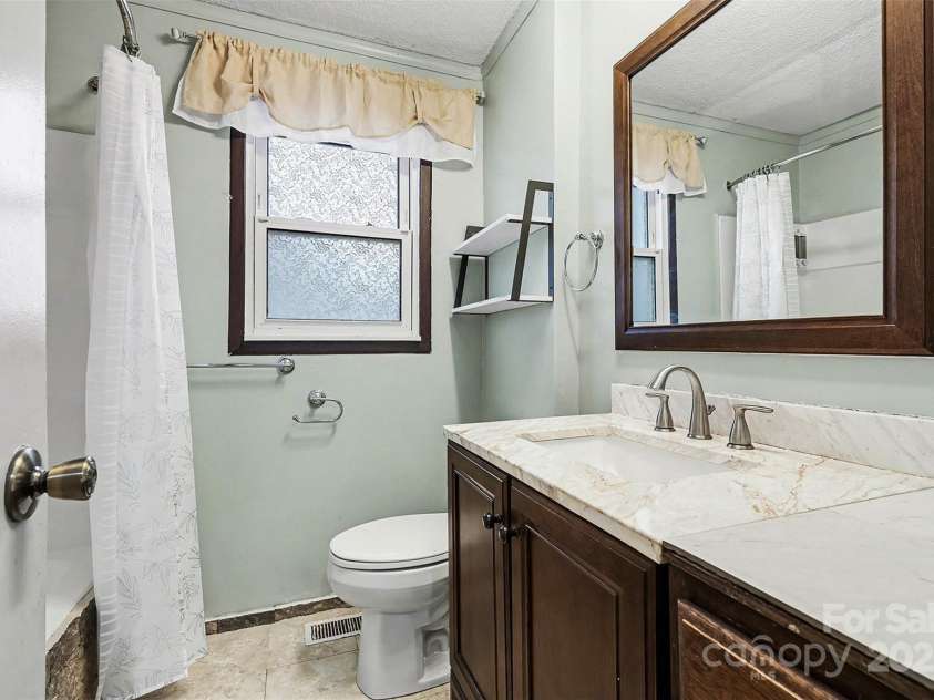 119 Moore Drive, Gastonia, NC 28056.  MLS# CAR4332115, YatesRealty ID 8565. Full bathroom featuring a single-sink vanity with solid-surface countertop and coordinating fixtures.