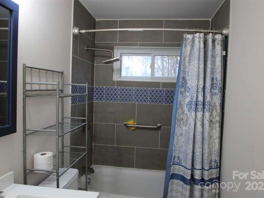 122 Lowry Row, York, SC 29745.  MLS# CAR4214035, YatesRealty ID 8886. A close up look of the tile surround tub with rainfall showerhead and a beautiful shower curtain