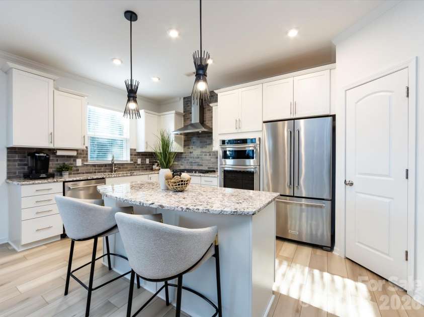 8903 Ansley Park Place, Huntersville, NC 28078.  MLS# CAR4366272, YatesRealty ID 8920. Chef’s kitchen featuring a large granite island with seating, stainless steel appliances, custom cabinetry, and stylish tile backsplash.