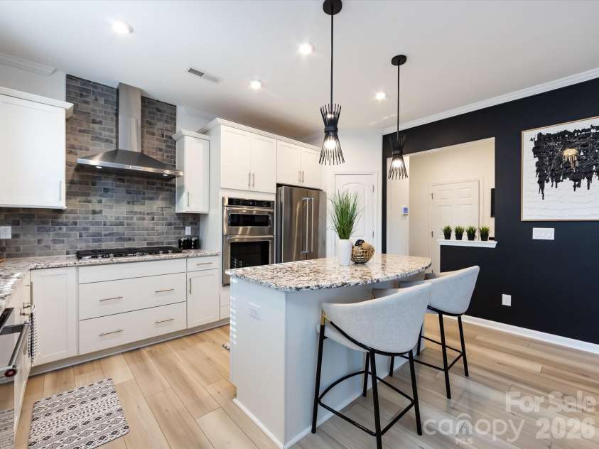 8903 Ansley Park Place, Huntersville, NC 28078.  MLS# CAR4366272, YatesRealty ID 8920. Chef’s kitchen featuring a large granite island with seating, stainless steel appliances, custom cabinetry, and stylish tile backsplash.