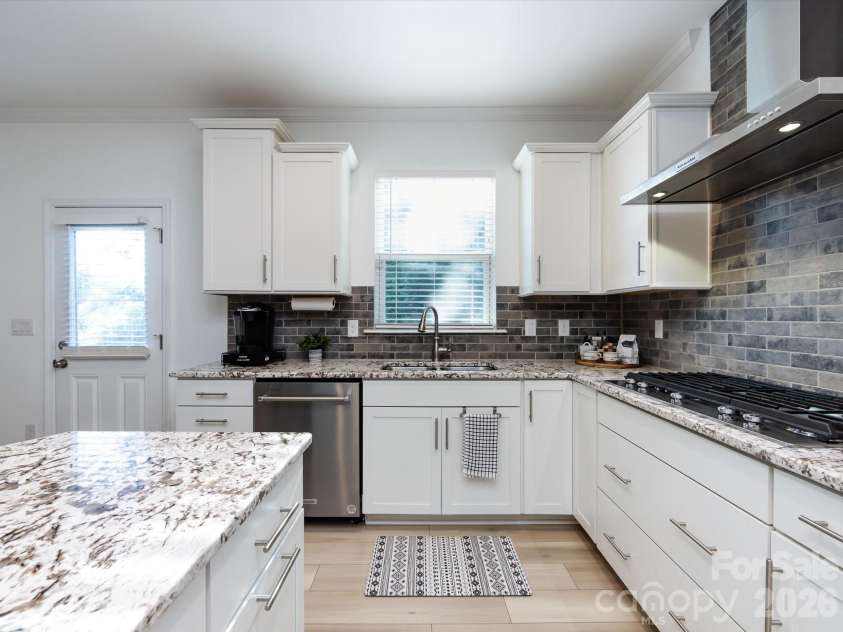 8903 Ansley Park Place, Huntersville, NC 28078.  MLS# CAR4366272, YatesRealty ID 8920. Chef’s kitchen featuring a large granite island with seating, stainless steel appliances, gas cooktop, custom cabinetry, and stylish tile backsplash.