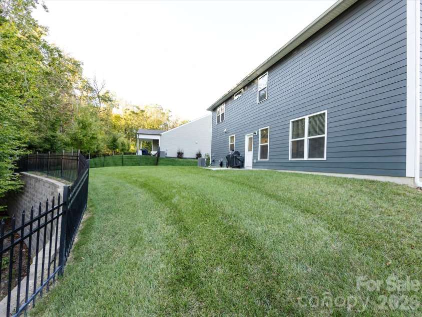 8903 Ansley Park Place, Huntersville, NC 28078.  MLS# CAR4366272, YatesRealty ID 8920. Spacious backyard with lush green lawn, mature trees, and fencing, offering privacy and room for outdoor enjoyment.