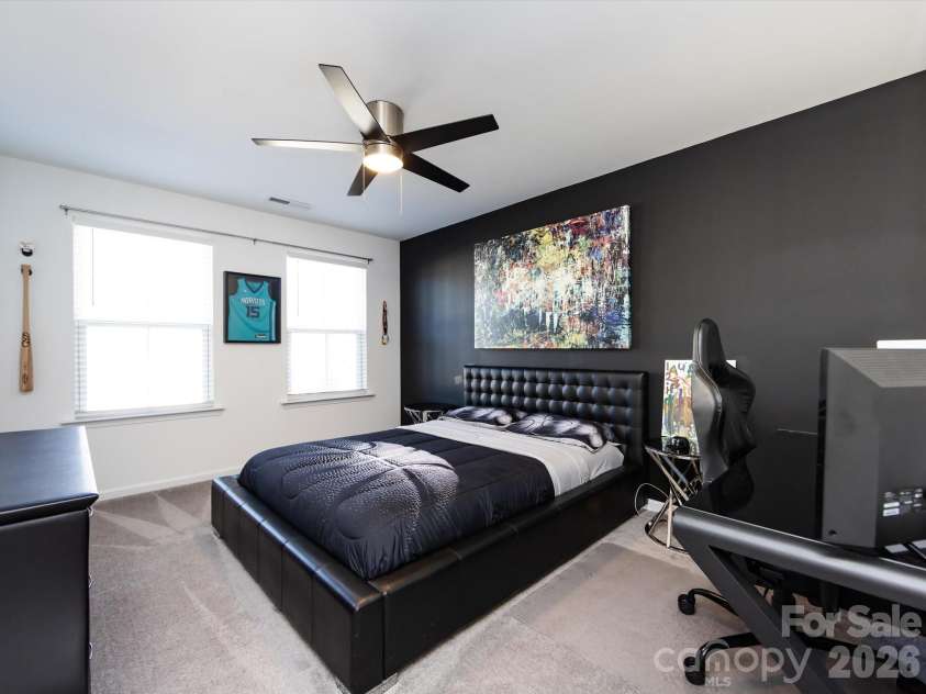 8903 Ansley Park Place, Huntersville, NC 28078.  MLS# CAR4366272, YatesRealty ID 8920. Spacious secondary bedroom featuring a stylish accent wall, ceiling fan, and ample natural light, perfect for guests or a home office.