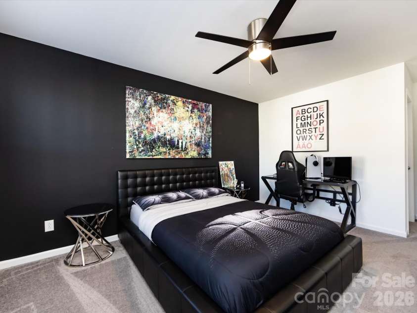8903 Ansley Park Place, Huntersville, NC 28078.  MLS# CAR4366272, YatesRealty ID 8920. Spacious secondary bedroom featuring a stylish accent wall, ceiling fan, and ample natural light, perfect for guests or a home office.