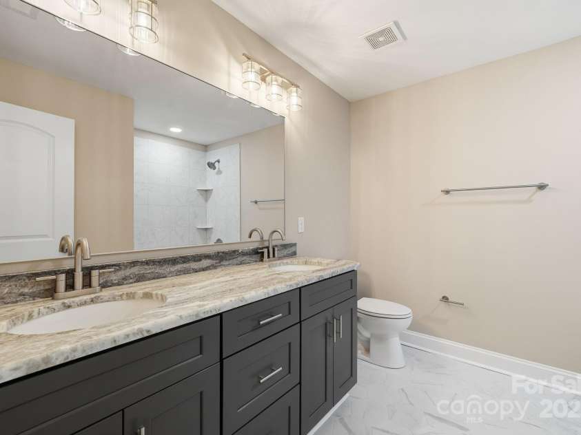 101 Mcalway Road, Charlotte, NC 28211.  MLS# CAR4321405, YatesRealty ID 896. Elegant guest bath with stone countertop and dual vanities.