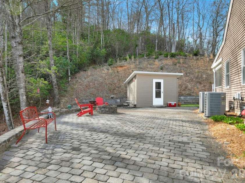 410 Forest Lake Road, Brevard, NC 28712.  MLS# CAR4364087, YatesRealty ID 9011. Side stone Patio/Wood Shed