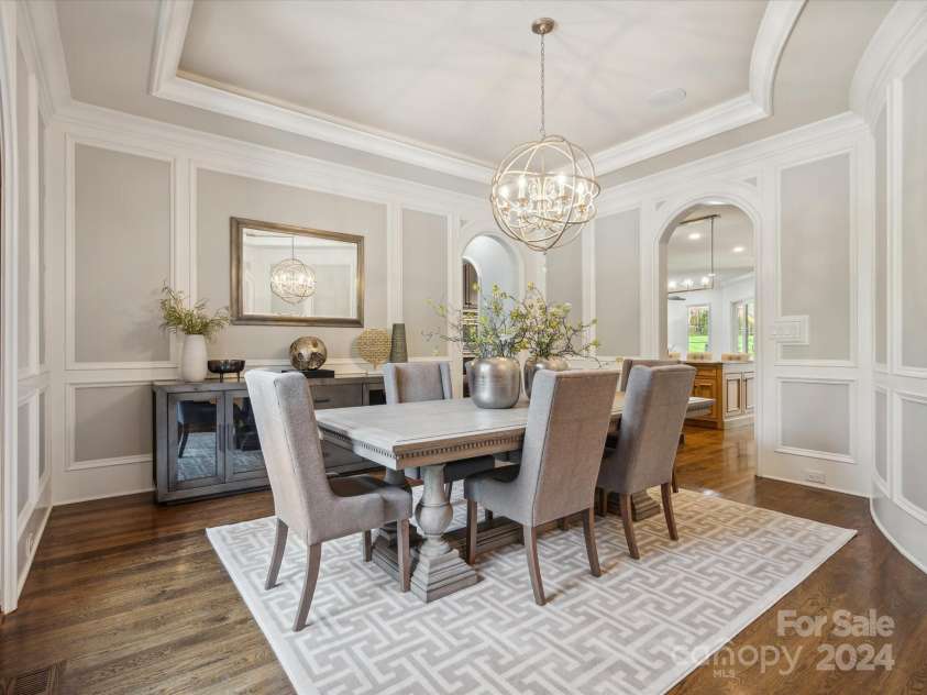 9044 Island Point Road, Charlotte, NC 28278.  MLS# CAR4135509, YatesRealty ID 912. The grand dining room, distinguished by its custom curved walls, elegant tray ceiling, and bespoke moldings, embodies the pinnacle of sophistication and elegance that befits such a distinguished setting