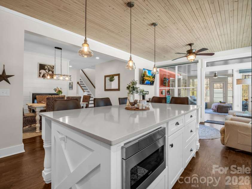 52 Old Spring Drive, Candler, NC 28715.  MLS# CAR4360930, YatesRealty ID 9363. Beautiful farmhouse kitchen gives a rustic luxury look, showing built-in microwave and looking into dining area with see-through gas fisreplace and to the right is the added 3-seasons sunroom