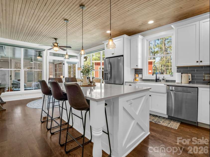 52 Old Spring Drive, Candler, NC 28715.  MLS# CAR4360930, YatesRealty ID 9363. Gorgeous chef's kitchen with quartz counters, room for 5 people (3 behind island and 2 on the side), stainless steel appliances, looking into the added 3 seasons sunroom
