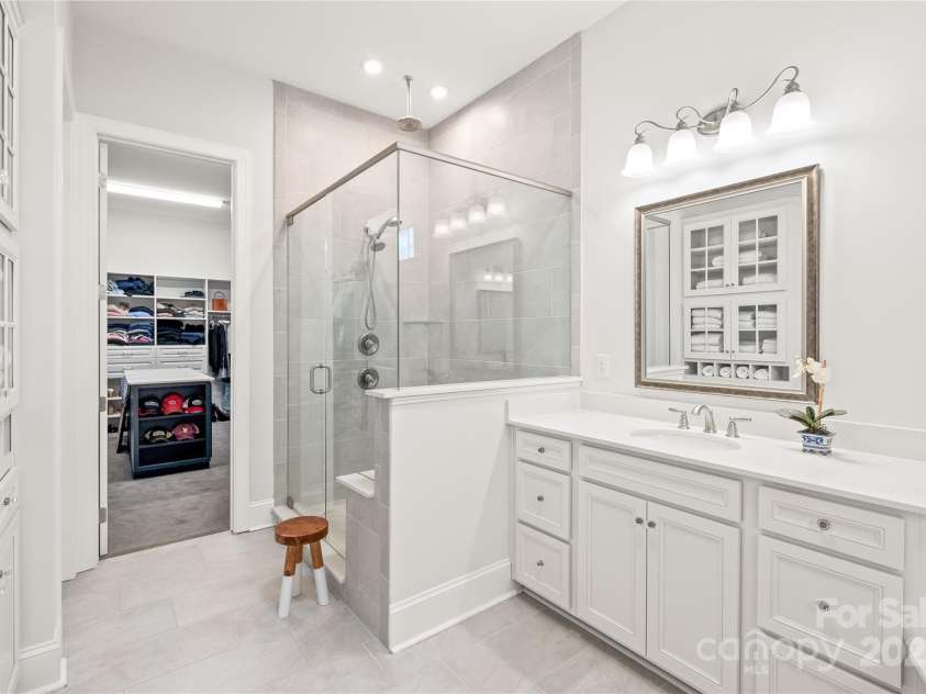 128 Shimmer Lake Lane, Belmont, NC 28012.  MLS# CAR4208573, YatesRealty ID 9390. Unwind in luxury! The walk-in, semi-frameless shower with a rain showerhead offers a spa-like experience, complemented by abundant cabinet storage and a dream custom walk-in closet with a stylish island.