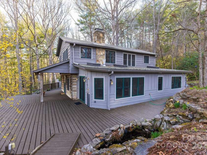 14 Woods Drive, Fairview, NC 28730.  MLS# CAR4223729, YatesRealty ID 9429. Side view of the home with an outdoor shower, waterfall and small pond.