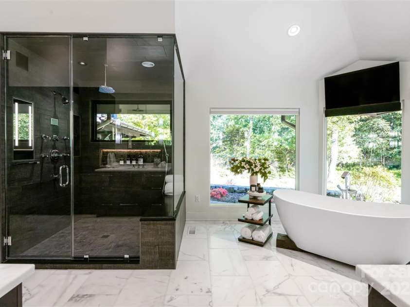 268 Holly Arbor Lane, Asheville, NC 28803.  MLS# CAR4268471, YatesRealty ID 97. The en-suite bath is luxury.  Featuring marble-topped custom vanities, a freestanding soaking tub with forest views, a steam-equipped oversized shower, radiant heated floors, and remote-controlled Hunter Douglas blinds f