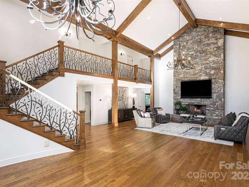 268 Holly Arbor Lane, Asheville, NC 28803.  MLS# CAR4268471, YatesRealty ID 97. The great room in the main house showcases a dramatic floor-to-ceiling stone gas fireplace, complemented by custom-forged iron handrails.