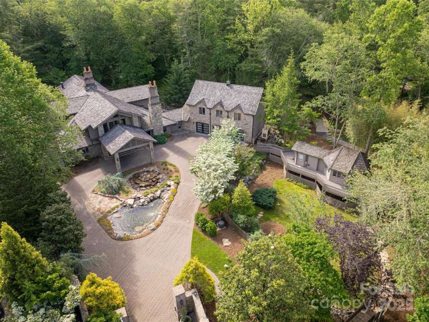 268 Holly Arbor Lane, Asheville, NC 28803.  MLS# CAR4268471, YatesRealty ID 97. The six-bedroom main house, nestled in a serene forest setting, is seamlessly connected to one of two charming guest cottages and welcomes you with a circular driveway and a picturesque pond and fountain.