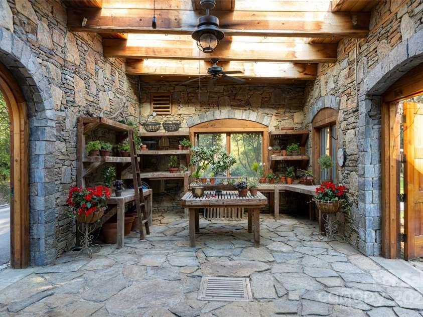 268 Holly Arbor Lane, Asheville, NC 28803.  MLS# CAR4268471, YatesRealty ID 97. The storybook stone conservancy, steeped in old-world charm, features a glass ceiling with roof windows,  cedar shelves and potting benches, and a serene, garden-facing ambiance. It also features 2 interior water spigots