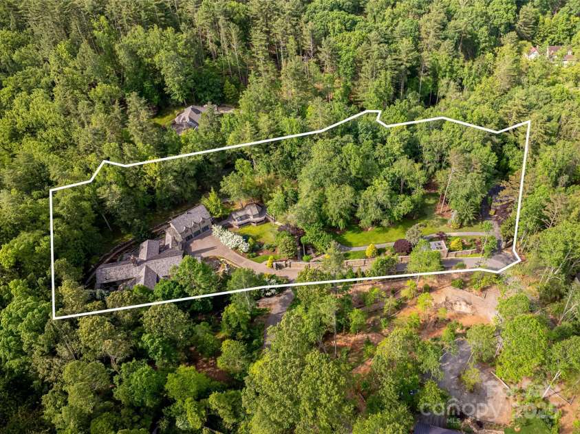 268 Holly Arbor Lane, Asheville, NC 28803.  MLS# CAR4268471, YatesRealty ID 97. This enchanting 4-acre estate showcases rolling meadows, fern-covered forests, and meticulously maintained gardens. The property includes a stately main house, two charming guest cottages, and a storybook stone conservan