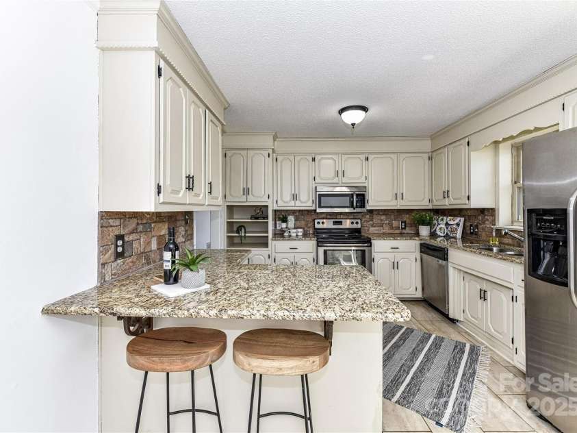 7770 Sherrills Ford Road, Sherrills Ford, NC 28673.  MLS# CAR4229083, YatesRealty ID 9721. Upgraded Kitchen features granite counters, stainless steel appliances, tile back splash, breakfast bar, plenty of cabinets for storage & breakfast area!