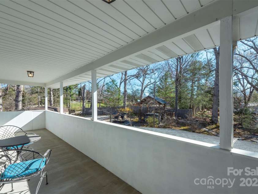 1740 Haywood Road, Hendersonville, NC 28791.  MLS# CAR4226897, YatesRealty ID 977. Covered porch accessible from the primary bedroom, where you can unwind, enjoy the outdoors, and listen to the soothing sounds of the water below.