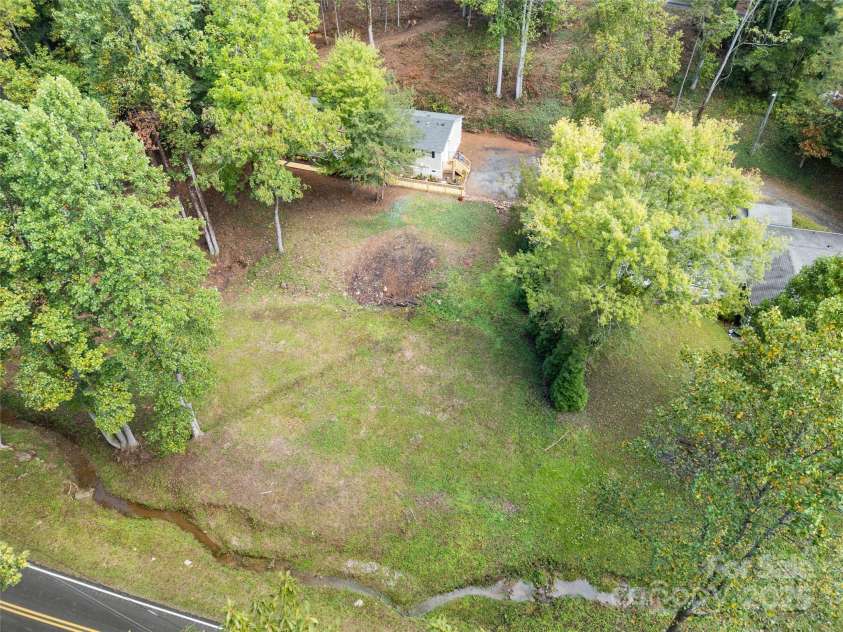 25 Overbrook Drive, Saluda, NC 28773.  MLS# CAR4306681, YatesRealty ID 981. From Laurel Drive and the stream, the yard rises up to the house. The back yard rises further up to touch mostly untraveled Overbrook Drive in the rear. 