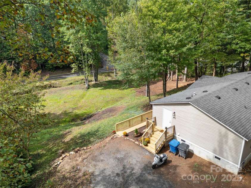 25 Overbrook Drive, Saluda, NC 28773.  MLS# CAR4306681, YatesRealty ID 981. This great looking roof is believed to have been installed in 2019.  This view shows the slope of the yard. Stream is lower on the lot and the house sits up nicely above any potential water. 